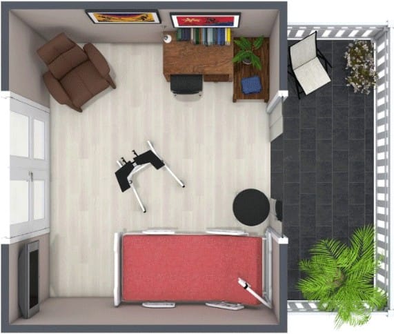 3D top-down view of a multi-purpose home office and assisted living room. The space includes a wooden desk with books and a plant, an assisted living bed with a red blanket and a grab rail, a foldable exercise bike, and a brown recliner chair. The adjacent balcony features black tiles, a lounge chair, and potted plants including a palm and a flowering bush.