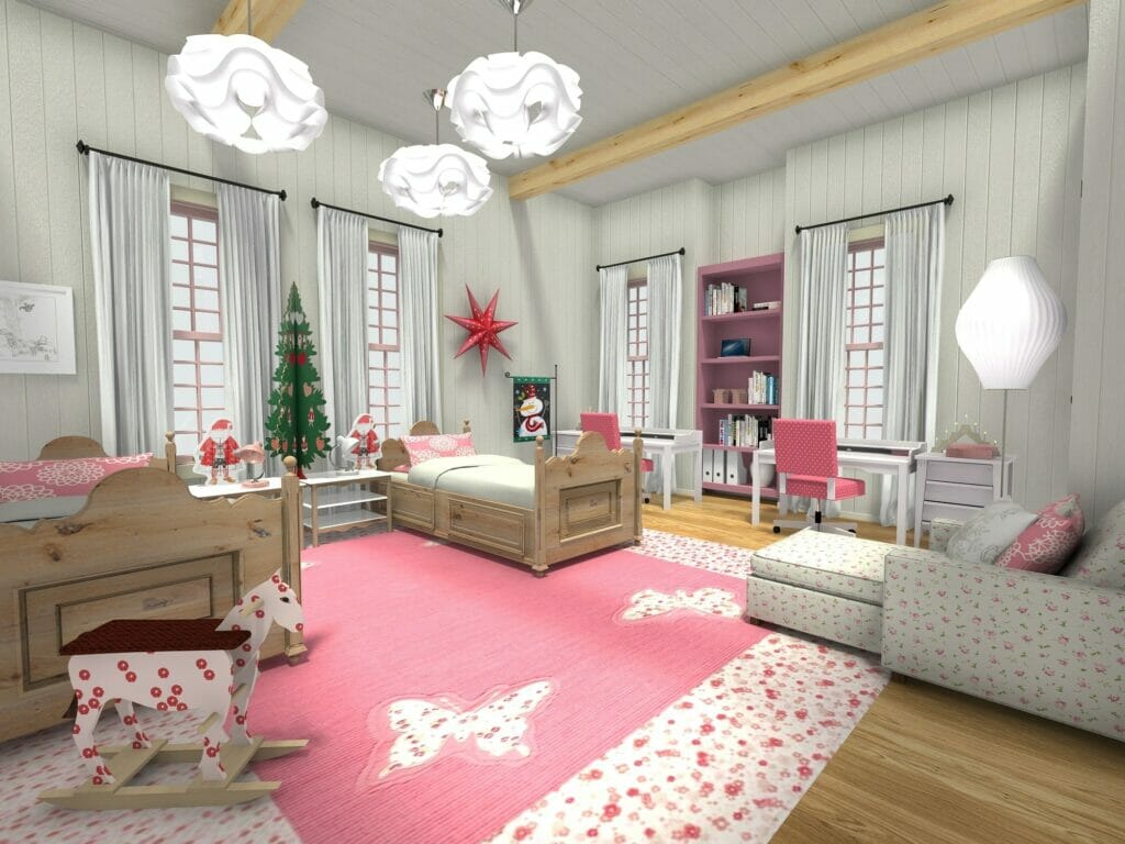 3D-rendered image of a festive and cozy children’s bedroom decorated for the holidays. The room features two wooden twin beds with pink bedding, a pink butterfly rug, a floral-patterned sofa, and a rocking horse. Christmas decorations include a felt tree, Santa figurines, and a red star hanging on the wall. A pair of study desks with pink chairs and a pink bookshelf are placed along the far wall between tall windows with white curtains. White sculptural pendant lights hang from a white ceiling with exposed wooden beams.
