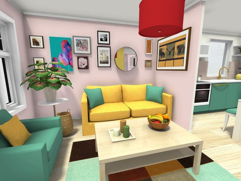 3D-rendered interior of a colorful living room created with interior design software. The room features a yellow sofa with teal accent pillows, a teal armchair, and a modern coffee table with candles and a bowl of fruit. The walls are light pink and decorated with an eclectic gallery of framed art and a round mirror. A red pendant lamp hangs above the table, and the open-plan layout reveals a kitchen with teal cabinets and gold fixtures in the background.