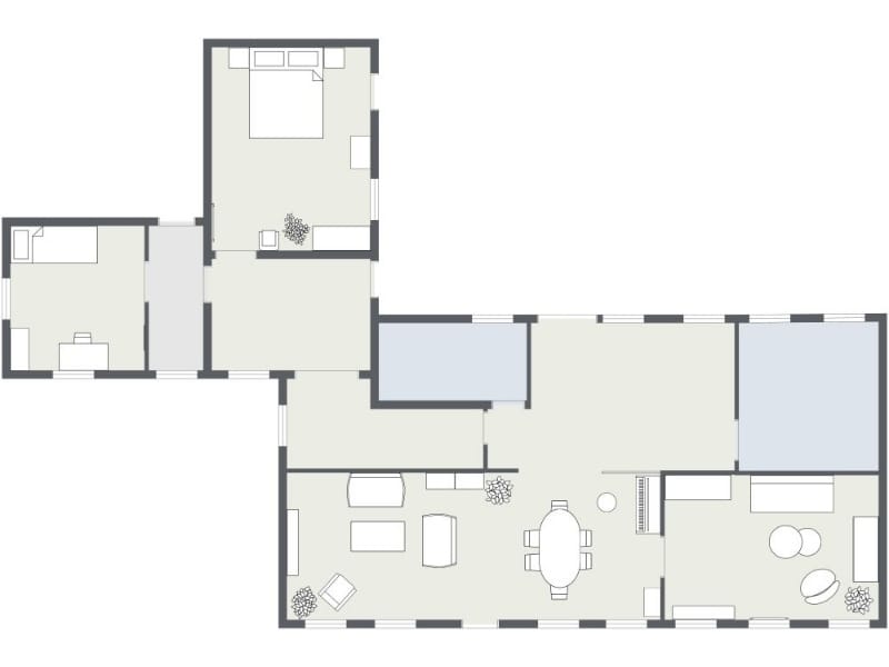 2D floor plan of a home showing multiple bedrooms, a central hallway, living room with seating, dining area, kitchen space, and additional rooms arranged in an extended layout.