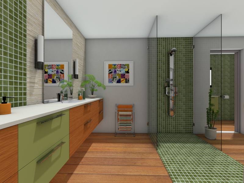 Modern bathroom with a walk-in glass shower featuring green mosaic tile that extends across the floor and up the wall. The space includes a long vanity with dual sinks, wood and olive green cabinetry, large mirrors, and wall-mounted lights. Warm wood flooring contrasts with the sleek tile and neutral walls. A colorful framed print and a potted plant add decorative touches.