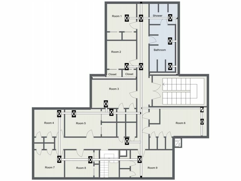 2D floor plan of a multi-room layout labeled with Room 1 through Room 9. The plan includes shared bathroom and shower areas, multiple closets, and stairwells. Each room is accessible via hallways, and there are several doors and ventilation or utility symbols marked throughout.