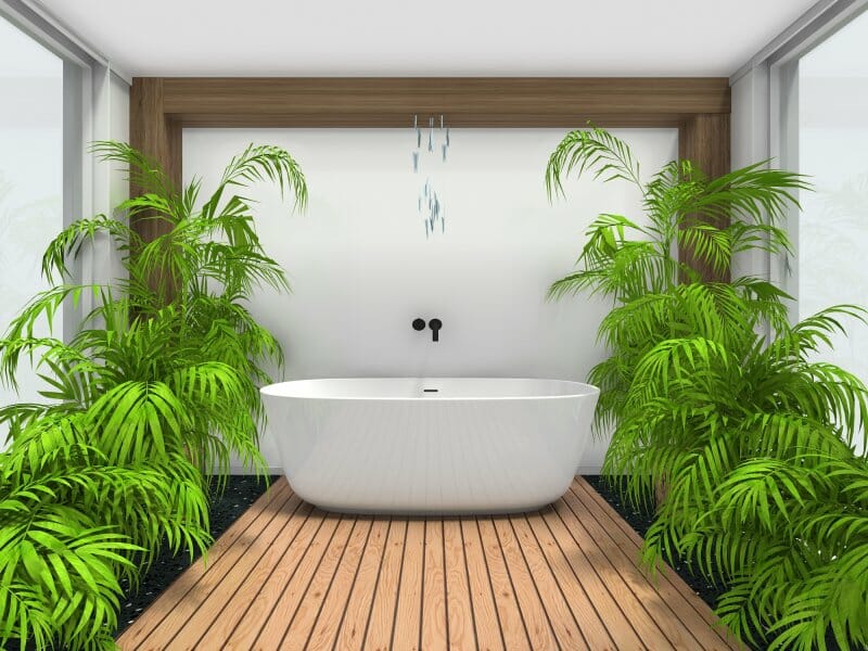 3D bathroom design created in the RoomSketcher app, featuring a white freestanding tub, wood flooring, and tropical plants on both sides.