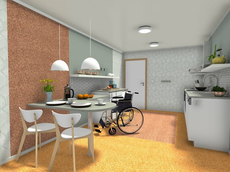 3D rendered view of an accessible kitchen and dining area designed for universal use. The space features a round dining table with three chairs, pendant lighting, and a wheelchair positioned at the table. The kitchen has lowered countertops, open shelving, and under-counter access to accommodate wheelchair users.